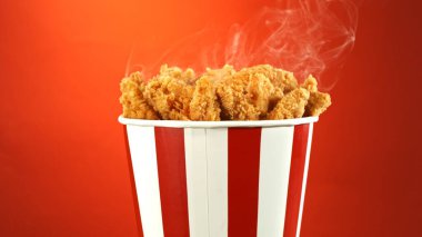 Kağıt kovada kızarmış tavuk parçaları, renkli arka planda izole edilmiş. Hurda Gıda Konsepti.