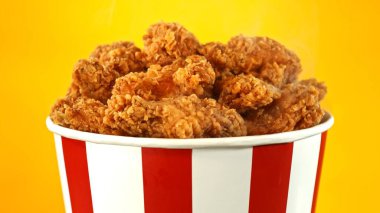 Kağıt kovada kızarmış tavuk parçaları, renkli arka planda izole edilmiş. Hurda Gıda Konsepti.