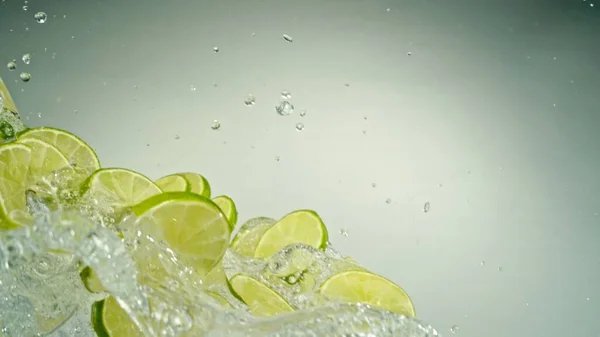 Jäädyttäminen Motion Flying Slices Limes Splashing Water Eristetty Harmaalla Pohjalla — kuvapankkivalokuva