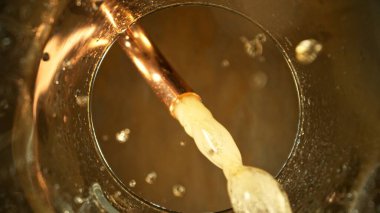Musluktan bardağa Macro Shot bira dökülüyor. Bir Bardağın Altından Eşsiz Bakış Açısı. Hareketi Dondur.