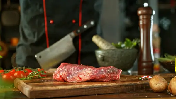 生ビーフステーキは木製の切断板で提供しました バックグラウンドで野菜を使った美味しいお肉 — ストック写真