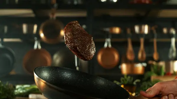 香喷喷的牛肉牛排从空中飞过来了 背景上有餐具的厨房 飞行食物的概念 免版税图库照片