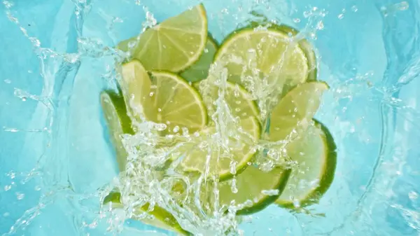Freeze Motion Lime Slices Falling Water Splashing Overhead Shot Fresh stockfoto
