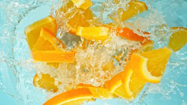 Frys Bevegelse Appelsinskiver Som Faller Vann Sprengning Overhead Skudd Frisk stockbilde