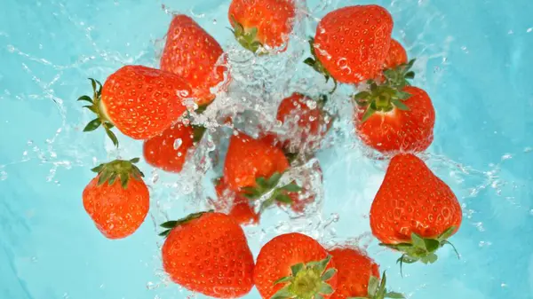 Gefrierbewegung Von Erdbeeren Die Ins Wasser Fallen Spritzen Frisches Obst Stockfoto