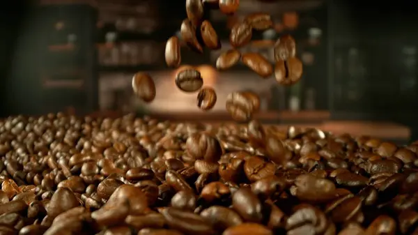 stock image Roasted coffee beans falling on heap. Close-up. Cafe interior on background.