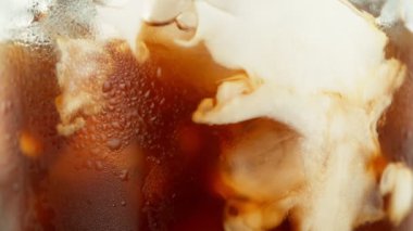 Buzlu kahve içeceğinin içine süt koymanın süper yavaş hareketi, yakın plan. Yüksek Hız Sinema Kamerası, 1000 fp..