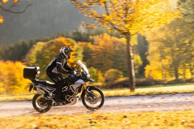 Motosikletçiler sonbahar ormanı manzaralı patikalarında gezerler. Macera ve off-road motor sporu. Ekstrem spor anlayışı, motor sporu