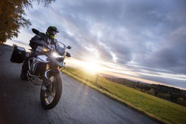 Asfalt yolda motosiklet yolculuğu. Sonbahar günbatımı, aksiyon çekimi.