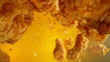 Altın Arkaplanda Uçan Kızarmış Tavuk Parçalarının Süper Yavaş Hareketi. Kamera Döndürür. Yüksek Hız Sineması Kamerası 'nda çekildi, 1000fps. Hız Rampası Efekti.