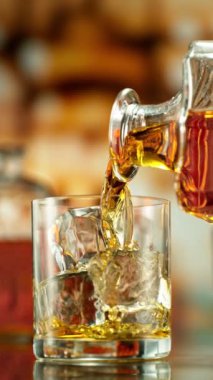 Viskiyi bardağa doldurmanın süper yavaş hareketi. High Speed Cinema Camera 'da çekildi, 1000 fps. Arkaplanda Bar, Odak Derinliği Düşük. Dikey Görünüm Oranı. Hareketli Kamera.