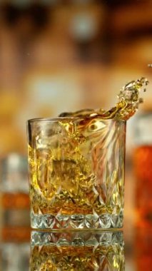 Bir bardak viskiye düşen buzun süper yavaş hareketi. High Speed Cinema Camera 'da çekildi, 1000 fps. Arkaplanda Bar, Odak Derinliği Düşük. Dikey Görünüm Oranı. Hız Rampası Efekti.