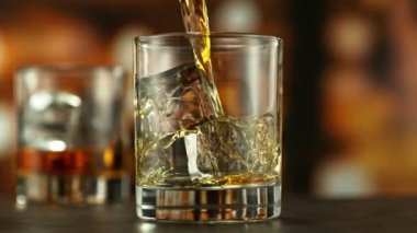 Viskiyi bardağa doldurmanın süper yavaş hareketi. High Speed Cinema Camera 'da çekildi, 1000 fps. Kamera Hareket Kontrol 'e yerleştirildi. Arkaplanda Bar, Odak Derinliği Düşük. Hız Rampası Efekti.