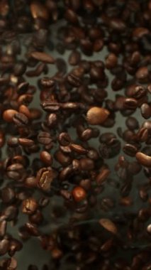 Yığının Üzerine Düşen Kahve Fasulyelerinin Süper Yavaş Hareketi. Kavrulmuş kahve çekirdeği kavramı. High Speed Cinema Camera 'da çekildi, 1000 fps. Dikey Görünüm Oranı.