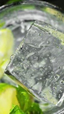 Ev yapımı limonataya Düşen Buz Küpü Süper Yavaş Hareketi. Yüksek Hız Sinema Kamerası, 1000 FPS, Hedef İzleme Kamerası. Dikey Görünüm Oranı.