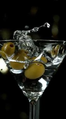 Zeytinlerin kokteyl içeceğine düşmesi, kamera hareketi. Yüksek hızlı sinema kamerası, 1000 fps. Hız rampası etkisi. Dikey Görünüm Oranı.
