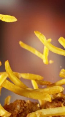 Flying Fried Chicken Wings ve patates kızartmalarının Süper Yavaş Hareketi. Arka plandaki Görüntü Özeti. Yüksek Hız Sineması Kamerası 'nda çekildi, 1000fps. Kamera hareket halinde. Dikey Görünüm Oranı.