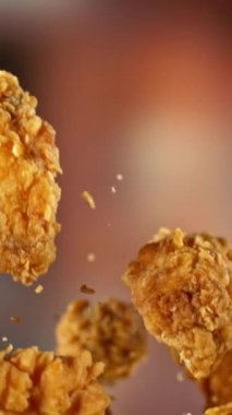 Uçan Kızarmış Tavuk Kanatları ve Parçalarının Süper Yavaş Hareketi. Arka plandaki Görüntü Özeti. Yüksek Hız Sineması Kamerası 'nda çekildi, 1000fps. Kamera hareket halinde. Dikey Görünüm Oranı.