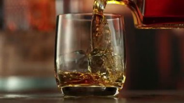 Viskiyi bardağa doldurmanın süper yavaş hareketi. High Speed Cinema Camera 'da çekildi, 1000 fps. Kamera Hareket Kontrol 'e yerleştirildi. Arkaplanda Bar, Odak Derinliği Düşük. Hız Rampası Efekti.