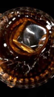Buz Küpü 'nün Kola İçeceği' ne Düşüşünün Süper Yavaş Hareketi. High Speed Cinema Camera 'da çekildi, 1000 fps. Dikey Görünüm Oranı.