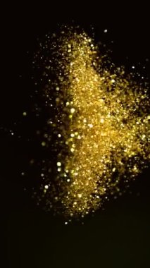 Siyah Arkaplan 'da izole edilmiş Süper Yavaş Parlayan Altın Parçacıklar Hareketi. Odaklanmanın Sığ Derinliği. High Speed Cinema Camera 'da çekildi, 1000 fps. Dikey Görünüm Oranı.