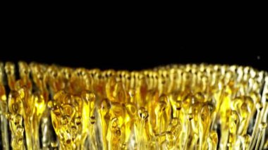 Kara Arkaplanda Su Sıçratan Yağlar Süper Yavaş Hareketi. Yüksek Hız Sineması Kamerası 'nda çekildi, 1000fps. Soyut Altın Yağ Damlaları, Güzellik veya Aşçılık Konsepti.