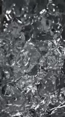 Siyah arka planda su sıçratmanın süper yavaş çekimi. Yüksek hızlı sinema kamerası, 1000 fps. Dikey görünüm oranı.