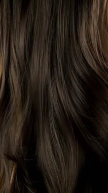 Dalgalı kahverengi saçları çok yavaş hareket ettiriyor. Yüksek hızlı sinema kamerası, 1000 fps. Dikey görünüm oranı.