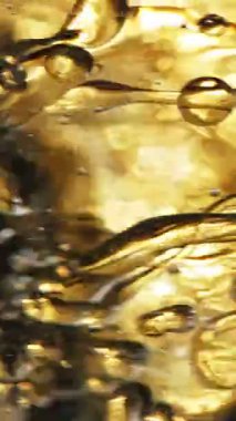 Su sıçratma yağının süper yavaş akışı. Makro soyut çekim. Yüksek hızlı sinema kamerasıyla çekildi, 1000fps. Dikey görünüm oranı.