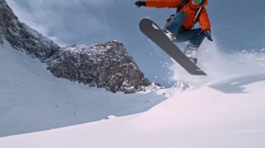 Piste Snowboardcusu atlayışı. Süper Yavaş Hareket, 1000 fp. Güneşli bir günde Piste Yamacında, Avrupa Alp Dağları 'nda açık mavi gökyüzüyle snowboard yapmak, Avusturya.