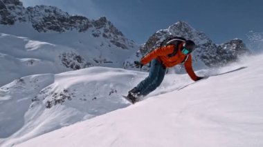 Piste Snowboardcusu 'nun orada. Süper Yavaş Hareket, 1000 fp. Avusturya 'nın Avrupa Alp Dağları' nda açık mavi gökyüzü ile güneşli bir günde Piste yamacında snowboard yapmak. Hız Rampası Efekti.