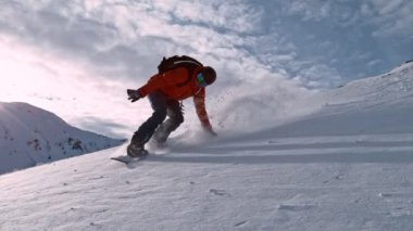 Piste Snowboardcusu 'nun orada. Süper Yavaş Hareket, 1000 fp. Güneşli bir günde Piste Yamacında, Avrupa Alp Dağları 'nda açık mavi gökyüzüyle snowboard yapmak, Avusturya.