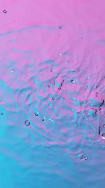 Neon ışıklarıyla aydınlatılmış su sıçratmanın süper yavaş çekimi. Yüksek hızlı sinema kamerası, dikey görünüm oranı.