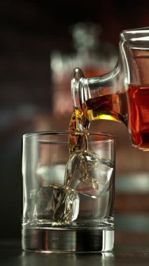 Viskiyi bardağa doldurmanın süper yavaş hareketi. High Speed Cinema Camera 'da çekildi, 1000 fps. Kamera Hareket Kontrol 'e yerleştirildi. Arkaplanda Bar, Odak Derinliği Düşük. Dikey Görünüm Oranı.