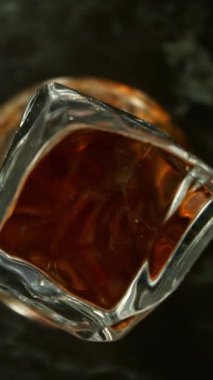 Buz Küpü 'nün Kola İçeceği' ne Düşüşünün Süper Yavaş Hareketi. Yüksek Hız Sinema Kamerası, 1000 FPS, Hedef İzleme Kamerası. Dikey Görünüm Oranı