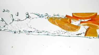 Süper Yavaş Uçan Portakal Dilimleri Su Sıçratır, Beyaz Arkaplan. High Speed Cinema Camera 'da çekildi, 1000 fps. Hız Rampası Efekti.