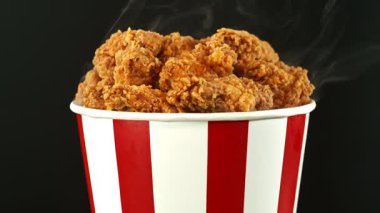 Renkli Arkaplanda Kova İçinde Yavaş Kızarmış Tavuk Parçaları Hareketi. Turntable 'da dönen dumanlı taze çıtır tavuk. Hız Rampası Efekti.