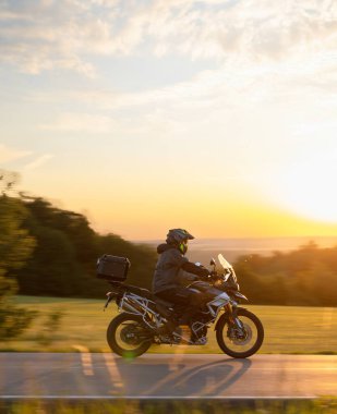 Motosikletçiler gün batımının güzel manzarasında gezerler. Dikey görünüm oranı.