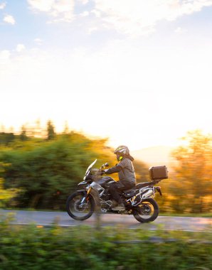 Motosikletçiler gün batımının güzel manzarasında gezerler. Dikey görünüm oranı.