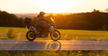 Güzel Günbatımı Işığıyla Yoldaki Motosiklet. Görüntü Görüntü Efektini arttırmak için arkaplan ve Önplan bulanıklaştırıldı. Kırsal Kırsal.