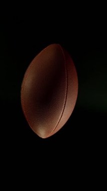 Hareket Eden Amerikan Futbol Topunun Süper Yavaş Hareketi. Kara Arkaplan 'da izole edilmiş. Üst Manzara. Yüksek Hız Sineması Kamerası 'nda çekildi, 1000fps. Dikey Görünüm Oranı.