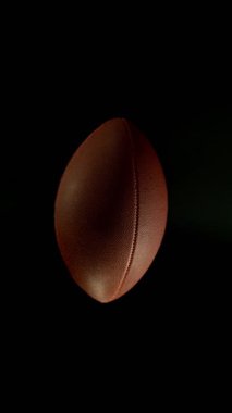 Hareket Eden Amerikan Futbol Topunun Süper Yavaş Hareketi. Kara Arkaplan 'da izole edilmiş. Üst Manzara. Yüksek Hız Sineması Kamerası 'nda çekildi, 1000fps. Dikey Görünüm Oranı.
