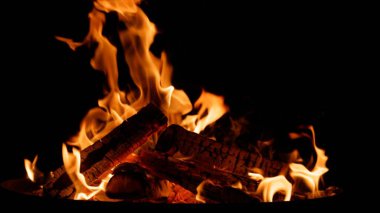 Siyah arka planda kıvılcımlar saçan Ateş Kampı alevleri. Gerçek ateşin dokusu.