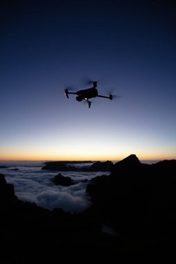 Drone Silhouette Sunset Light 'ta. Arka planda Yüksek Dağlar ve Vadide Bulutlar. Açık gökyüzü, Düşük Işık, Seçici Odak.