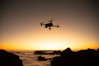 Drone Silhouette Sunset Light 'ta. Arka planda Yüksek Dağlar ve Vadide Bulutlar. Açık gökyüzü, Düşük Işık, Seçici Odak.