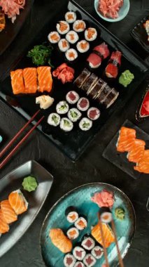 Kamera Hareketli Suşi Parçalarının Üst Manzarası. Taze Japon suşisi, Asya mutfağı konsepti. Topladığı insanlar. Kara Taş Masa 'ya yerleştirilmiş. Kamera Hareket Kontrol Sistemi 'ne Yerleştirildi.