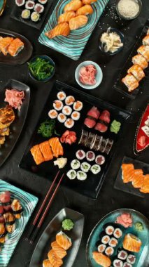 Kamera Hareketli Suşi Parçalarının Üst Manzarası. Taze Japon suşisi, Asya mutfağı konsepti. Topladığı insanlar. Kara Taş Masa 'ya yerleştirilmiş. Kamera Hareket Kontrol Sistemi 'ne Yerleştirildi.