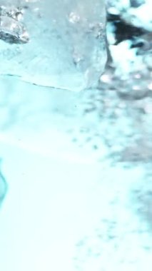 Suda dönen buz küplerinin süper yavaş hareketi. Yüksek hızlı sinema kamerası, 1000 fps. Sualtı bileşimi. Dikey görünüm oranı.