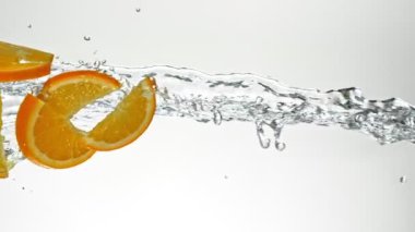 Süper Yavaş Uçan Portakal Dilimleri Su Sıçratır, Beyaz Arkaplan. Yüksek Hız Sinema Kamerası, 1000 fp.. 