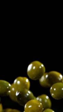 Uçan ve Dönen Yeşil Zeytinlerin Süper Yavaş Hareketi. High Speed Cinema Camera 'da çekildi, 1000 fps. Dikey Görünüm Oranı. Kara Arkaplanda İzole Edilmiş.